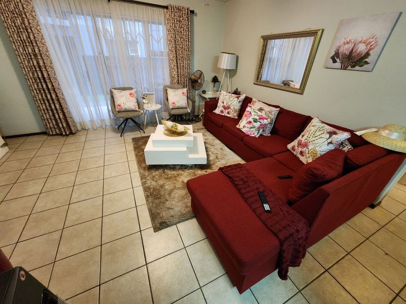 A comfortable living room featuring tiled flooring and a large sliding glass door that provides access to the outdoor area.