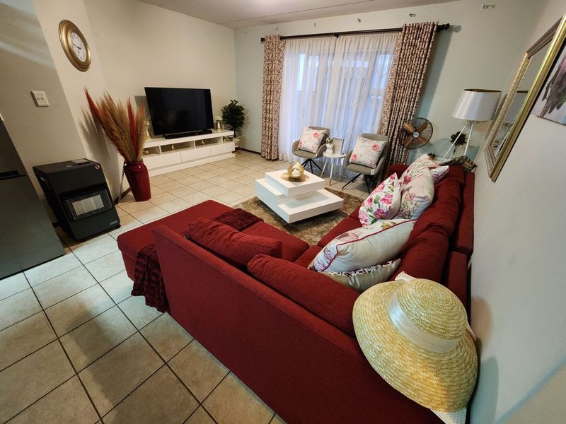 A comfortable living room featuring tiled flooring, a freestanding fireplace, and large sliding glass doors that provide access to the outdoor area.