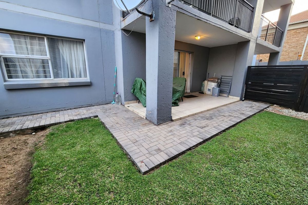 A ground floor apartment rear patio featuring paved flooring, a sliding door entrance, and access to a small private garden area.
