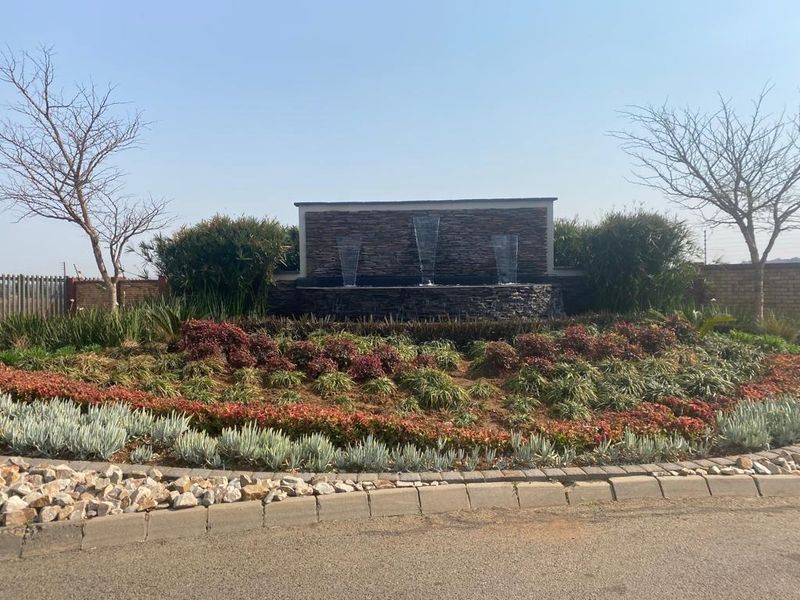 A well-maintained landscaped garden area featuring a decorative stone-clad water feature and established plantings, providing an attractive entrance or focal point.