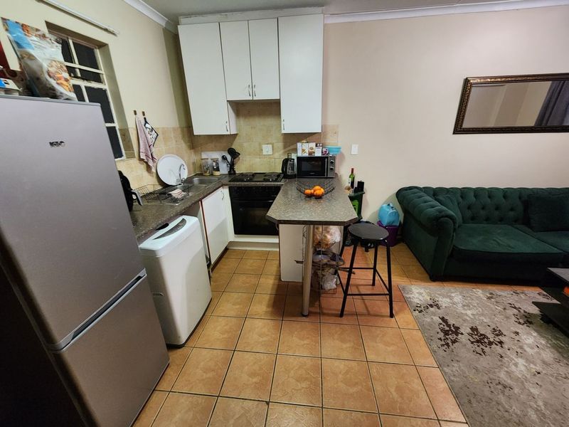 Open-plan kitchen and living area featuring tiled flooring, built-in cabinetry, and a breakfast bar counter.