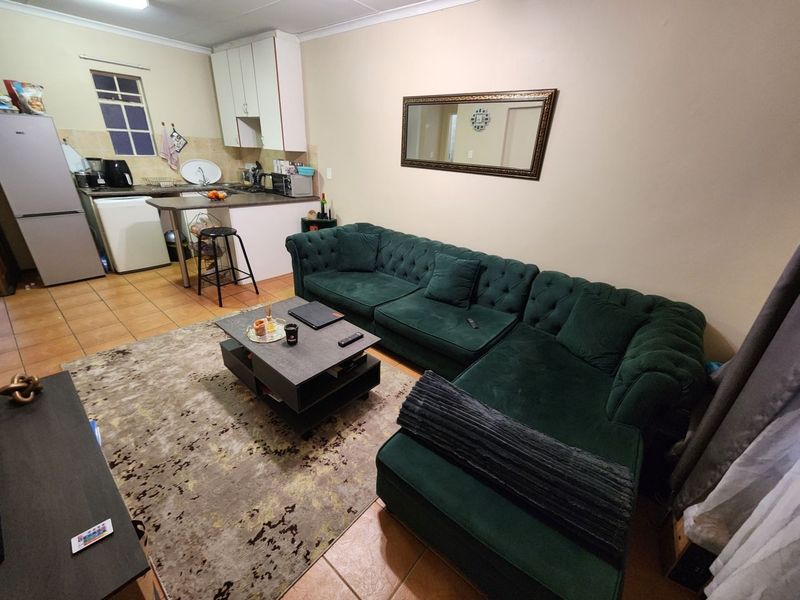 Open-plan living area featuring tiled flooring and a compact kitchen with built-in cabinetry and a breakfast counter.