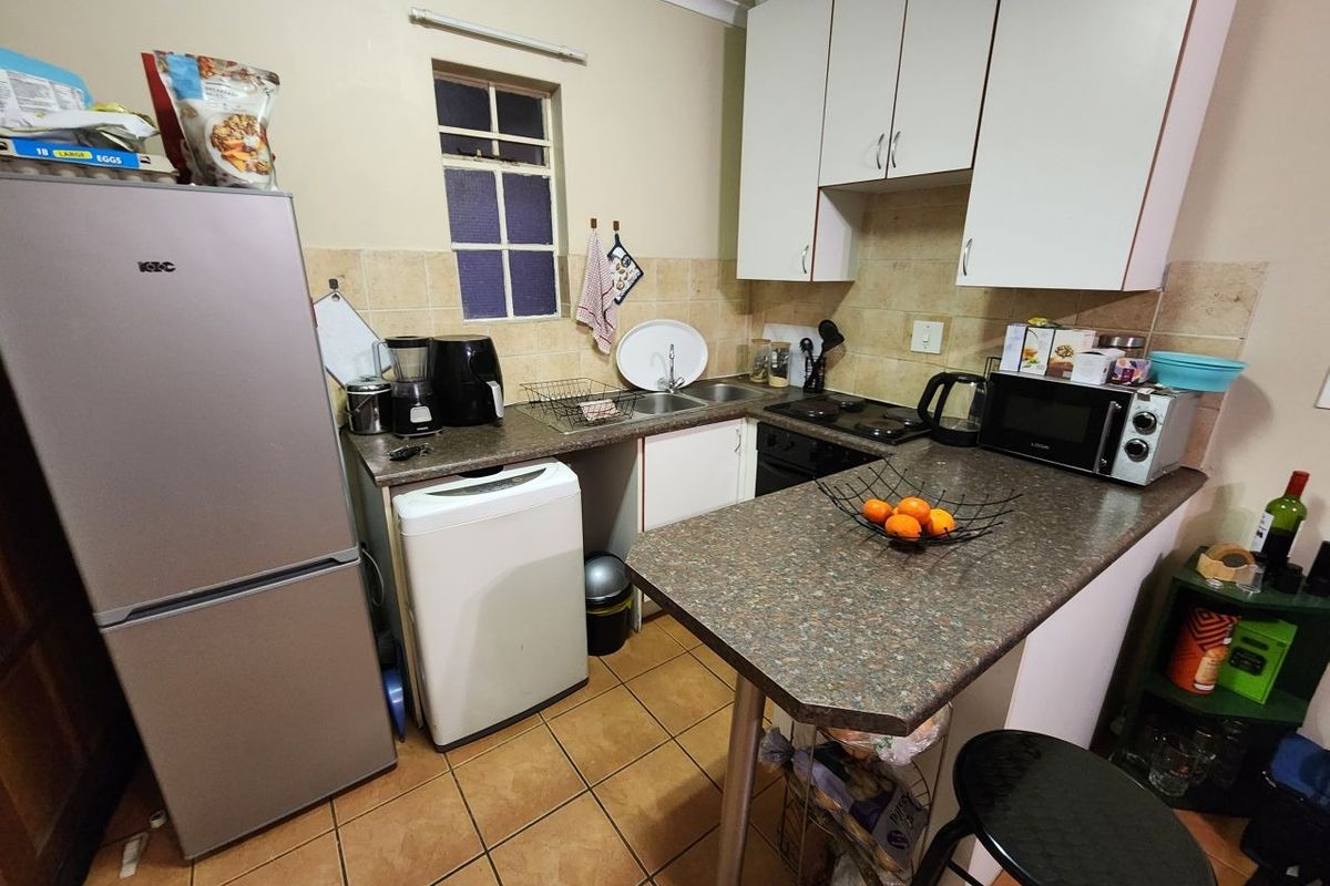 Compact kitchen featuring laminate countertops, built-in cabinetry, double basin sink, and tiled backsplash with ceramic flooring.