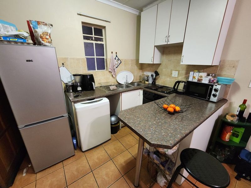 Compact kitchen featuring laminate countertops, built-in cabinetry, double basin sink, and tiled backsplash with ceramic flooring.
