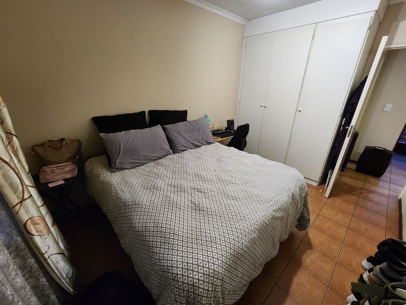 A functional bedroom featuring built-in cupboards and tiled flooring, providing a practical living space.