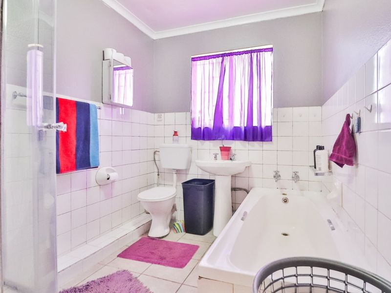 A functional bathroom featuring a pedestal basin, bathtub, and separate shower enclosure with white wall tiling and neutral paint.