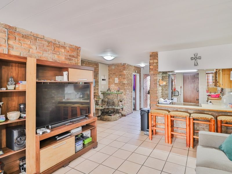 Open plan living and kitchen area featuring exposed brick walls, ceramic tiled flooring, and a breakfast bar counter.