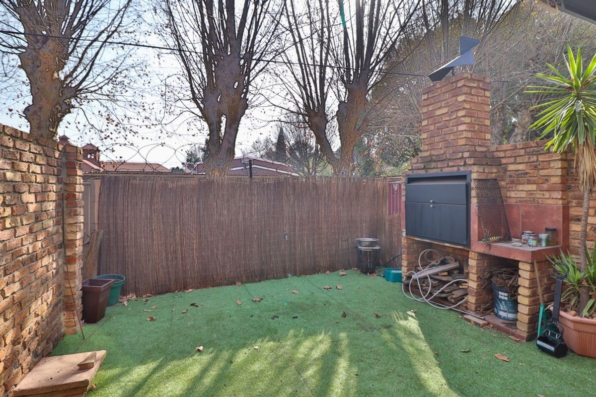 Private rear courtyard featuring a built-in brick braai, artificial lawn, and secure perimeter walling.
