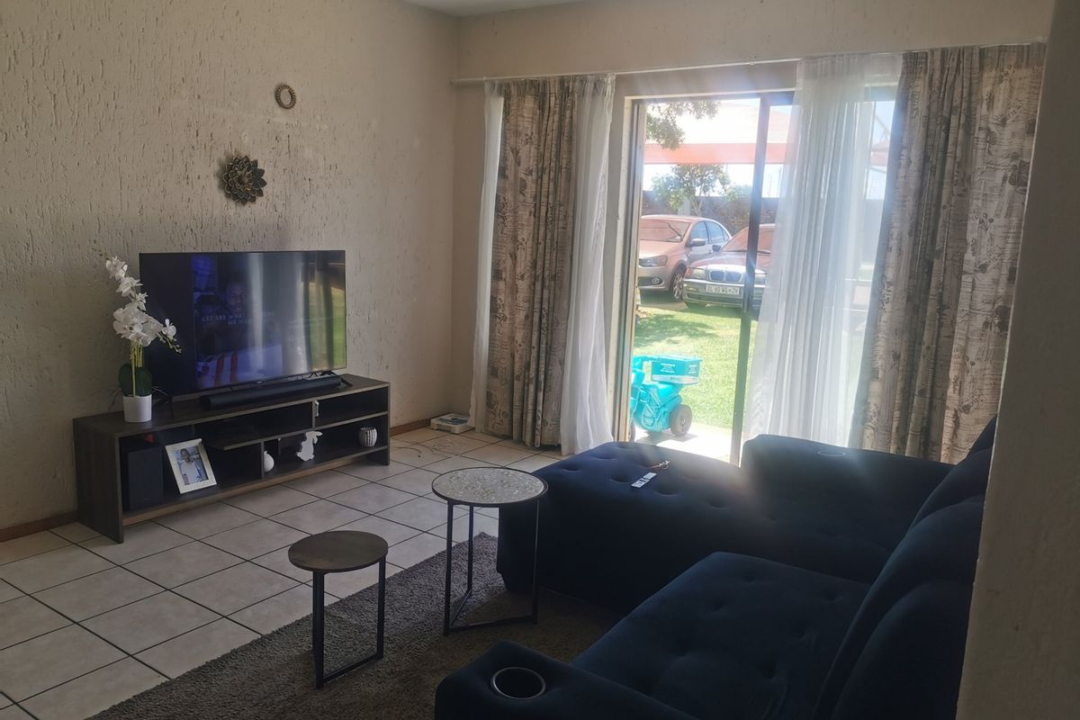 A living room featuring tiled flooring and a sliding glass door providing access to the exterior.