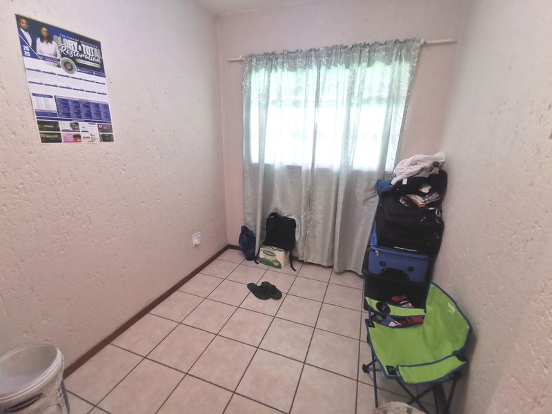 A compact bedroom featuring tiled flooring and a window with a curtain rod, offering a blank canvas for potential interior design updates.
