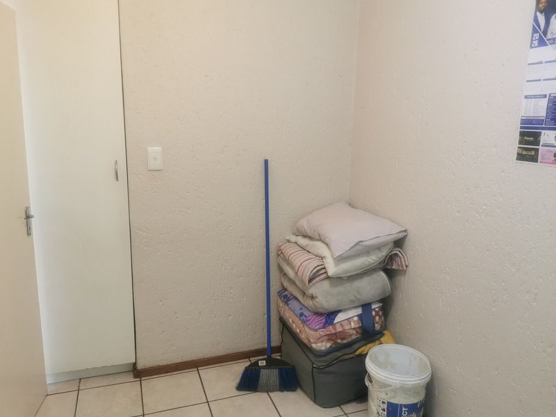 A simple bedroom space featuring tiled flooring and a built-in cupboard, providing a functional and neutral foundation for personalization.