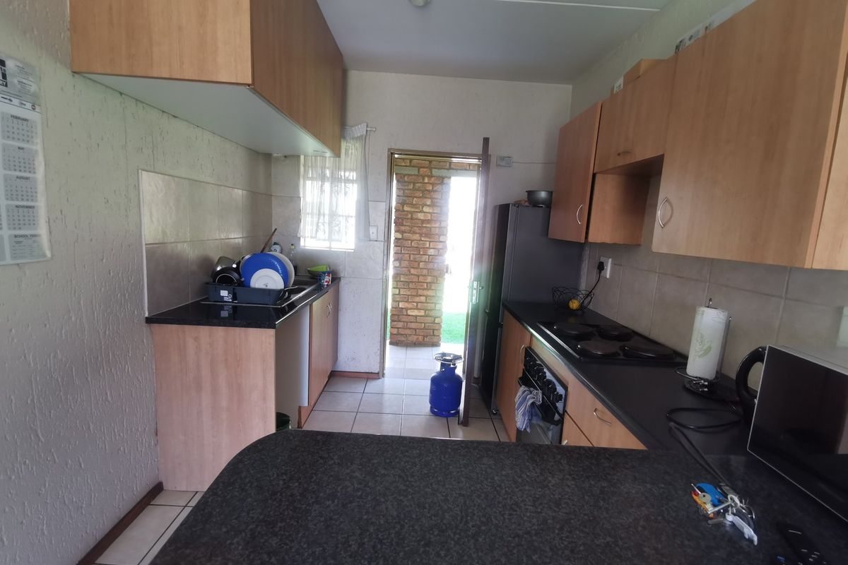 A functional kitchen featuring laminate cabinetry, dark countertops, built-in oven and hob, tiled backsplash, and direct access to an exterior area.
