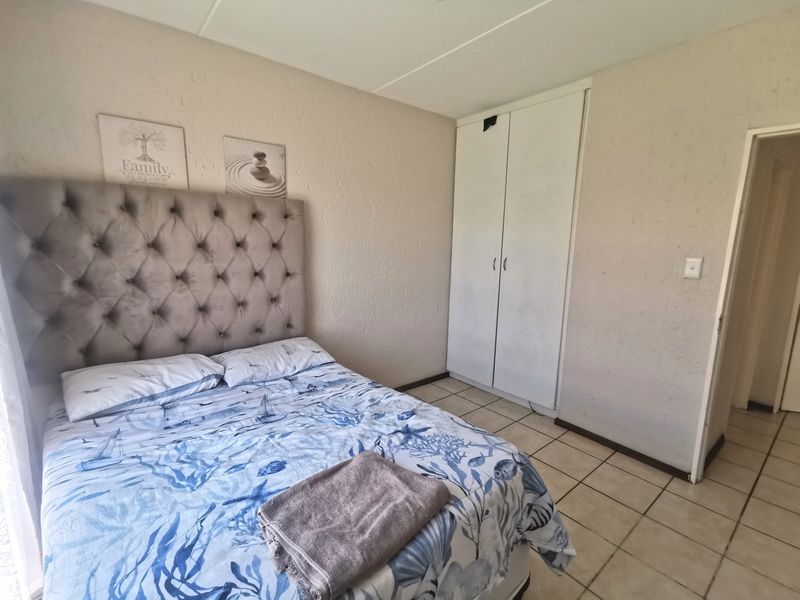 A bedroom featuring tiled flooring and a built-in wardrobe, offering a functional space with neutral wall finishes.