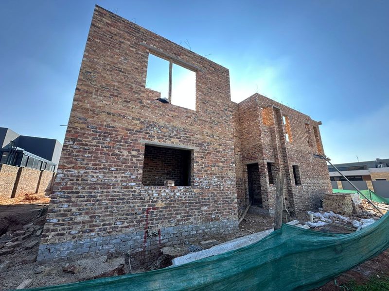 A view of a residential property currently under construction, featuring exposed brickwork and structural masonry walls.