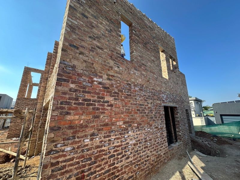 Exterior view of a residential property currently under construction, featuring exposed brickwork and structural walling.