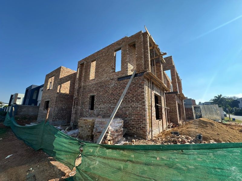 A residential property currently under construction, featuring exposed brickwork and structural framing in an early development phase.