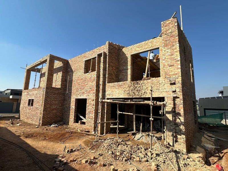 A double-story residential property currently under construction, featuring exposed brickwork and structural scaffolding on the rear elevation.
