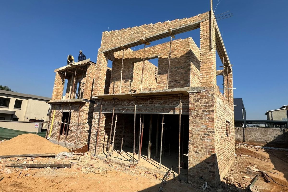 A residential property currently under construction, showing the exposed brick structure and framework of a two-story house.