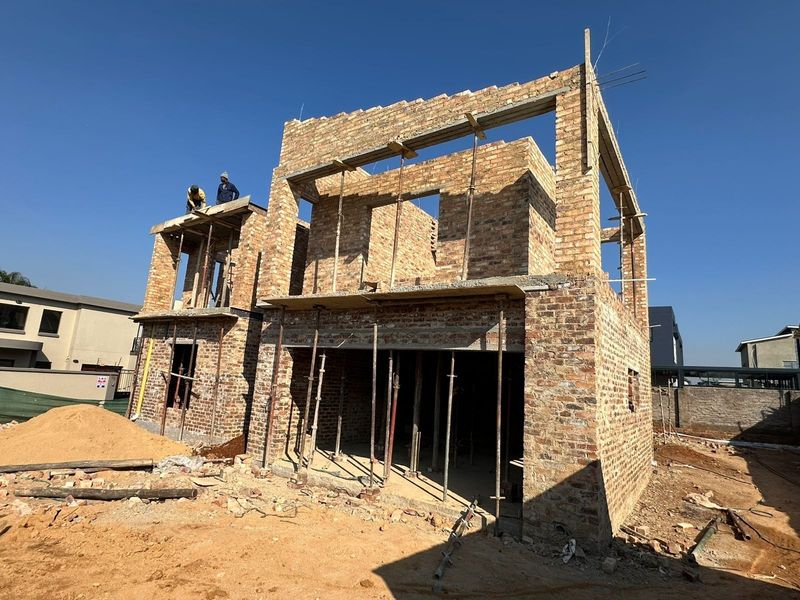 A residential property currently under construction, showing the exposed brick structure and framework of a two-story house.