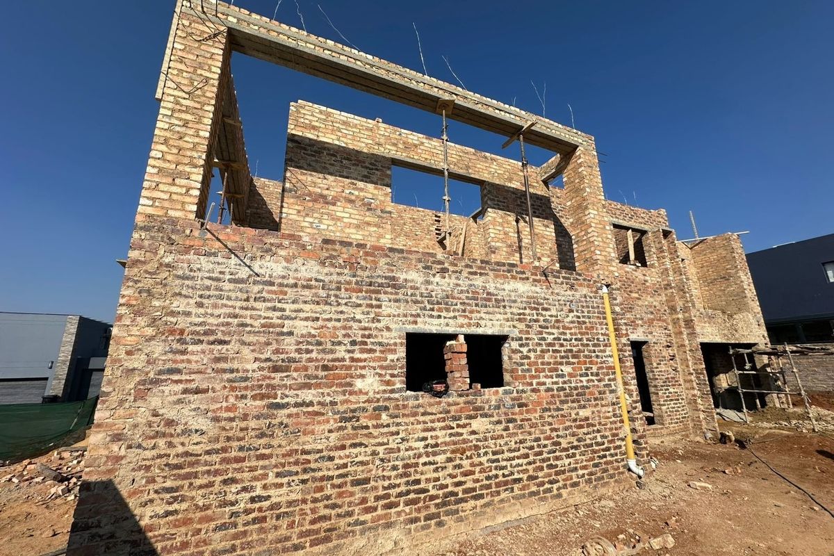 A rear view of a residential property currently under construction, featuring exposed brickwork and structural concrete lintels.