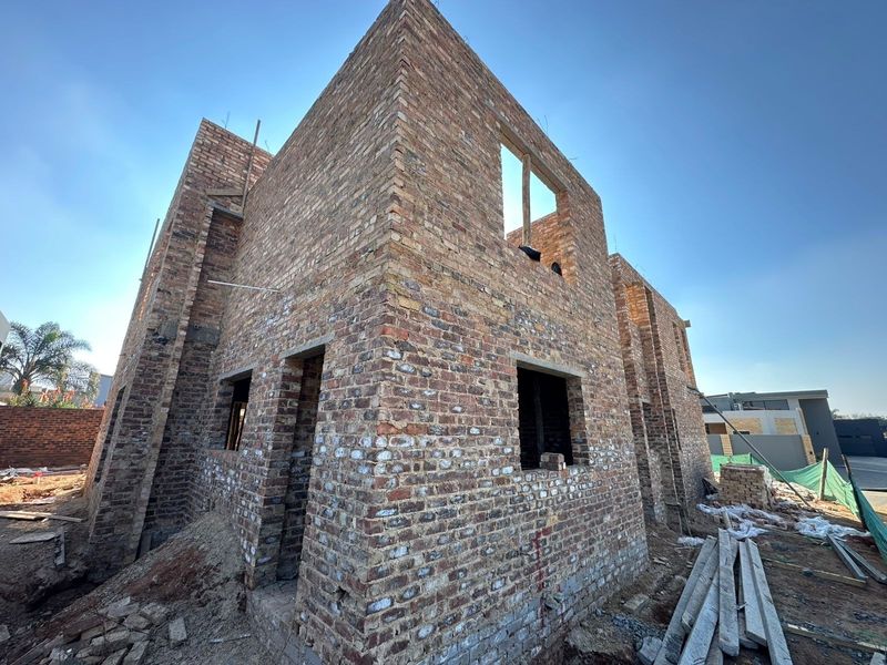 A two-story residential property currently under construction, featuring exposed brickwork and structural framing in an early development phase.