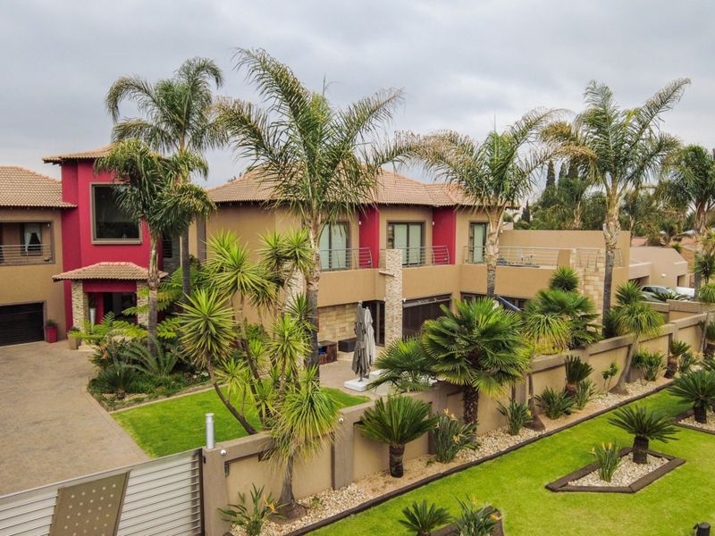 A well-maintained double-story residential property featuring a paved driveway, landscaped garden, boundary wall, and a spacious balcony.