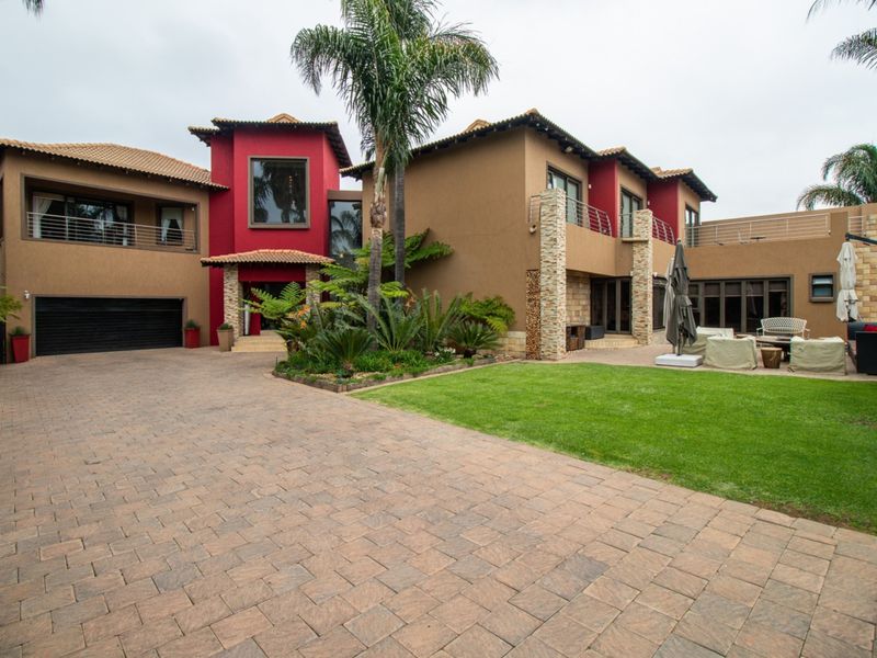 A well-maintained double-story residence featuring a paved driveway, double garage, stone-clad accents, and a landscaped front garden with balcony access.