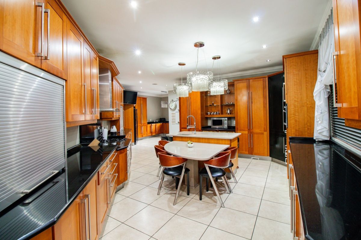 Spacious kitchen featuring extensive wooden cabinetry, granite countertops, a central island with integrated seating, and modern built-in appliances.