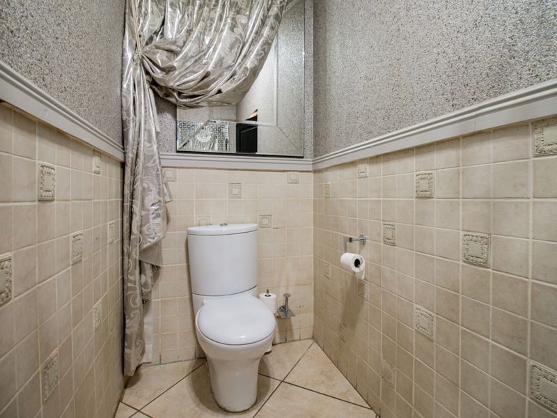 A compact guest bathroom featuring tiled walls, tiled flooring, and a wall-mounted mirror.