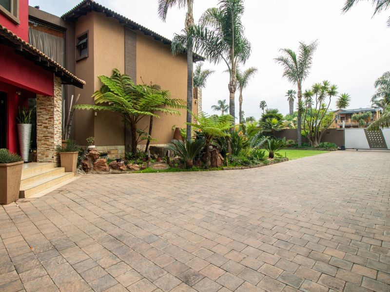 Spacious paved driveway leading to the front entrance, featuring stone cladding accents and established garden landscaping.