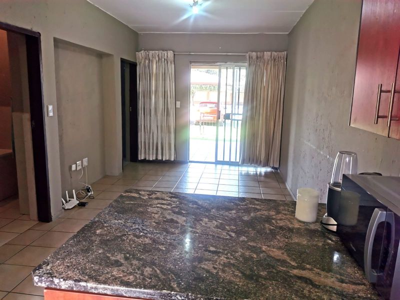 Open plan living area featuring tiled floors, granite kitchen countertops, and a sliding glass door leading to the exterior.