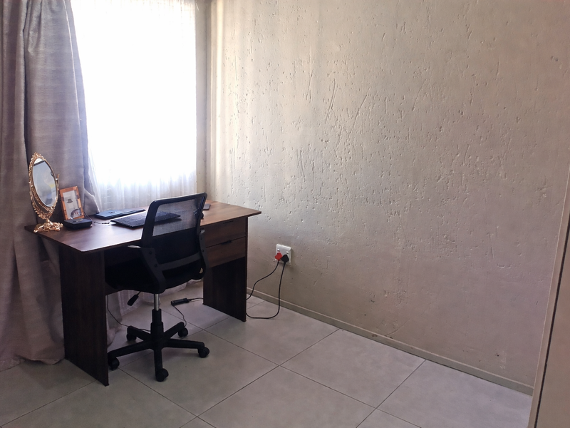 A functional office space featuring tiled flooring and a textured wall finish, providing a neutral area suitable for a home workspace.