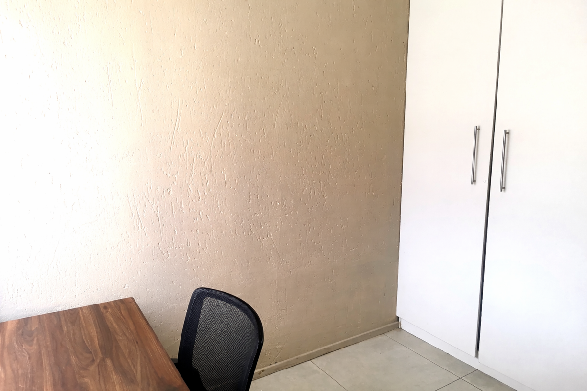 A bedroom featuring tiled flooring and a built-in wardrobe with white doors.