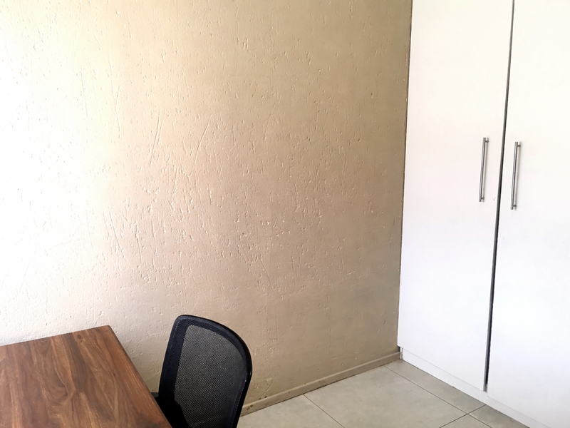 A bedroom featuring tiled flooring and a built-in wardrobe with white doors.