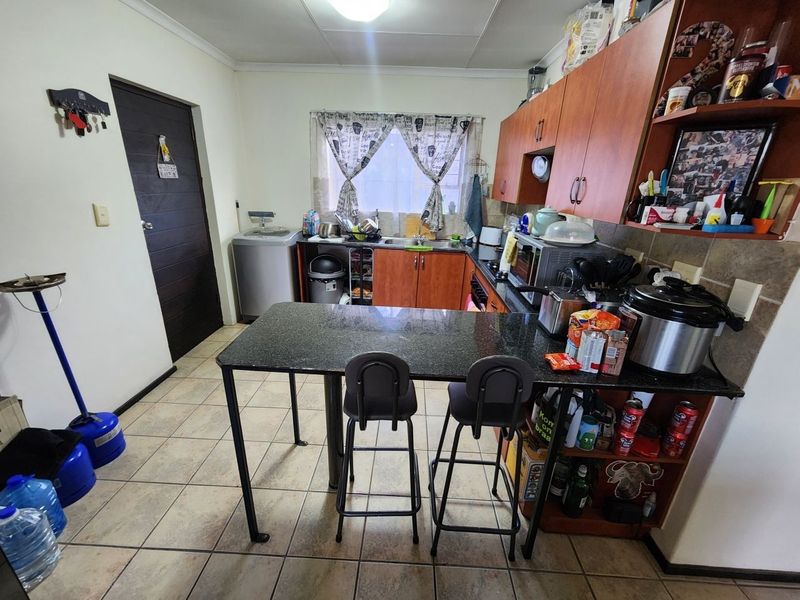 A functional kitchen featuring laminate cabinetry, granite countertops, a built-in breakfast bar, and tiled flooring, offering a practical layout for daily use.