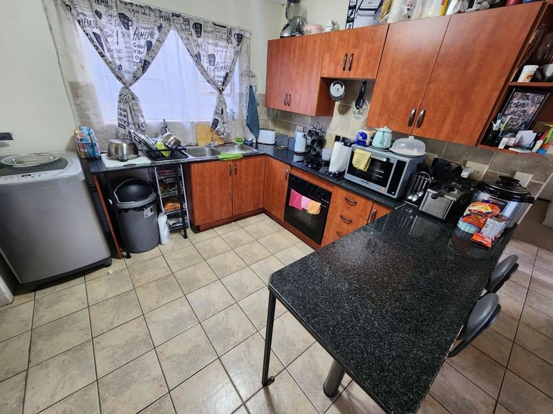 A functional kitchen featuring laminate cabinetry, granite countertops, a built-in oven, and a tiled backsplash with a breakfast bar area.