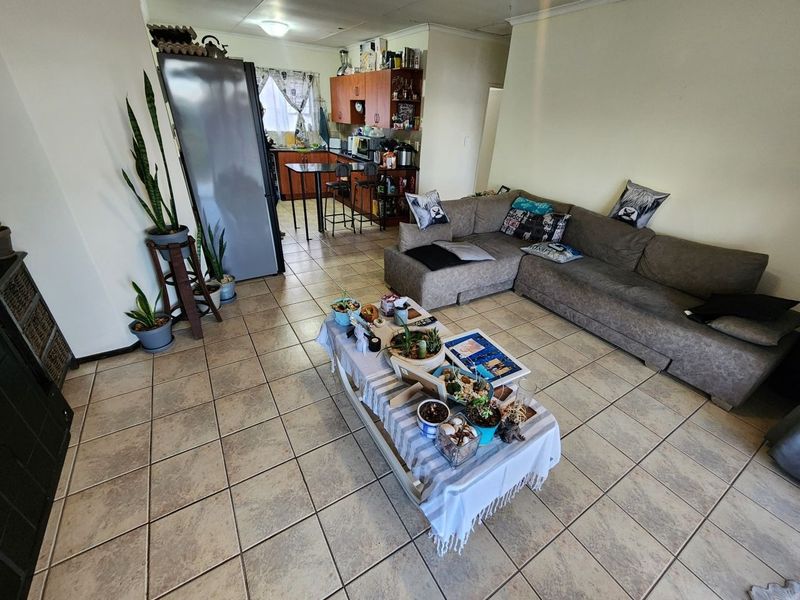 Open plan living area featuring tiled flooring and an integrated kitchen with wooden cabinetry, providing a functional and connected living space.