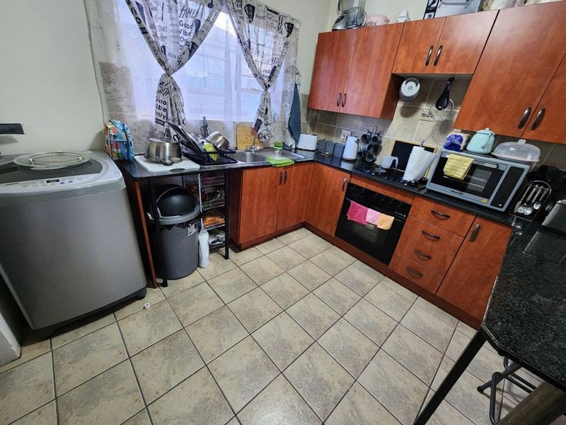 A functional kitchen featuring wood-finish cabinetry, granite countertops, a built-in oven, and tiled flooring, offering a practical layout for daily meal preparation.