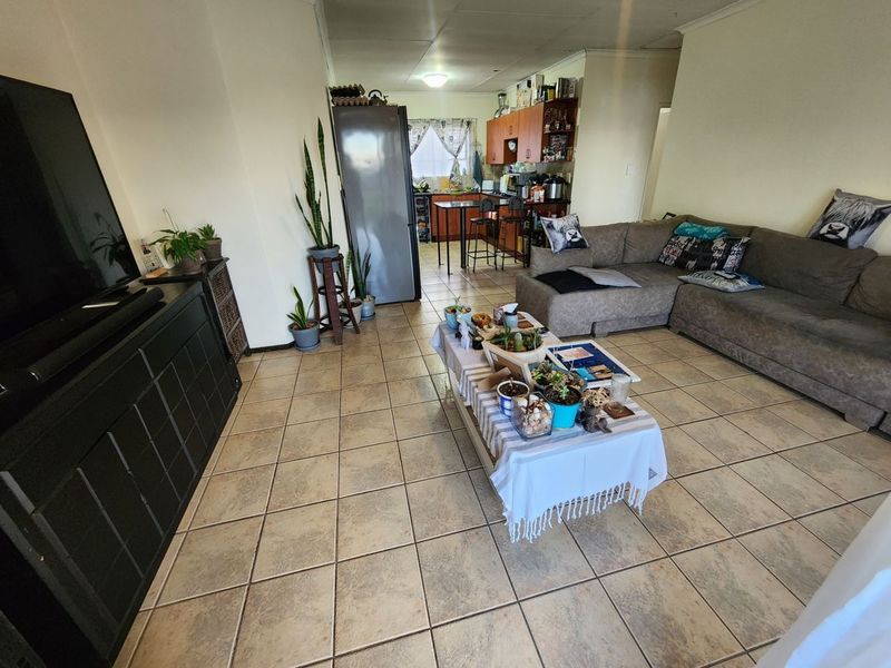 An open-plan living and kitchen area featuring tiled flooring, built-in cabinetry, and a breakfast counter, offering a functional layout for daily living.