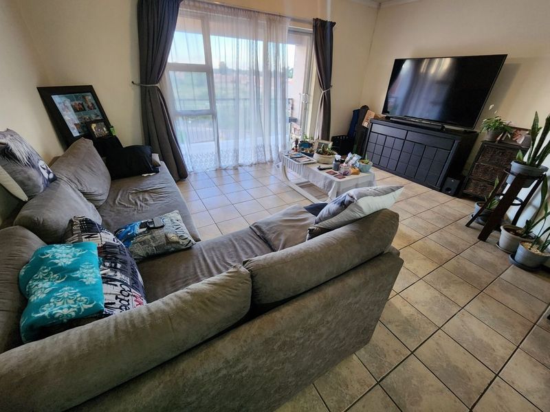 A living room featuring tiled flooring and a large sliding glass door that provides access to an outdoor area.