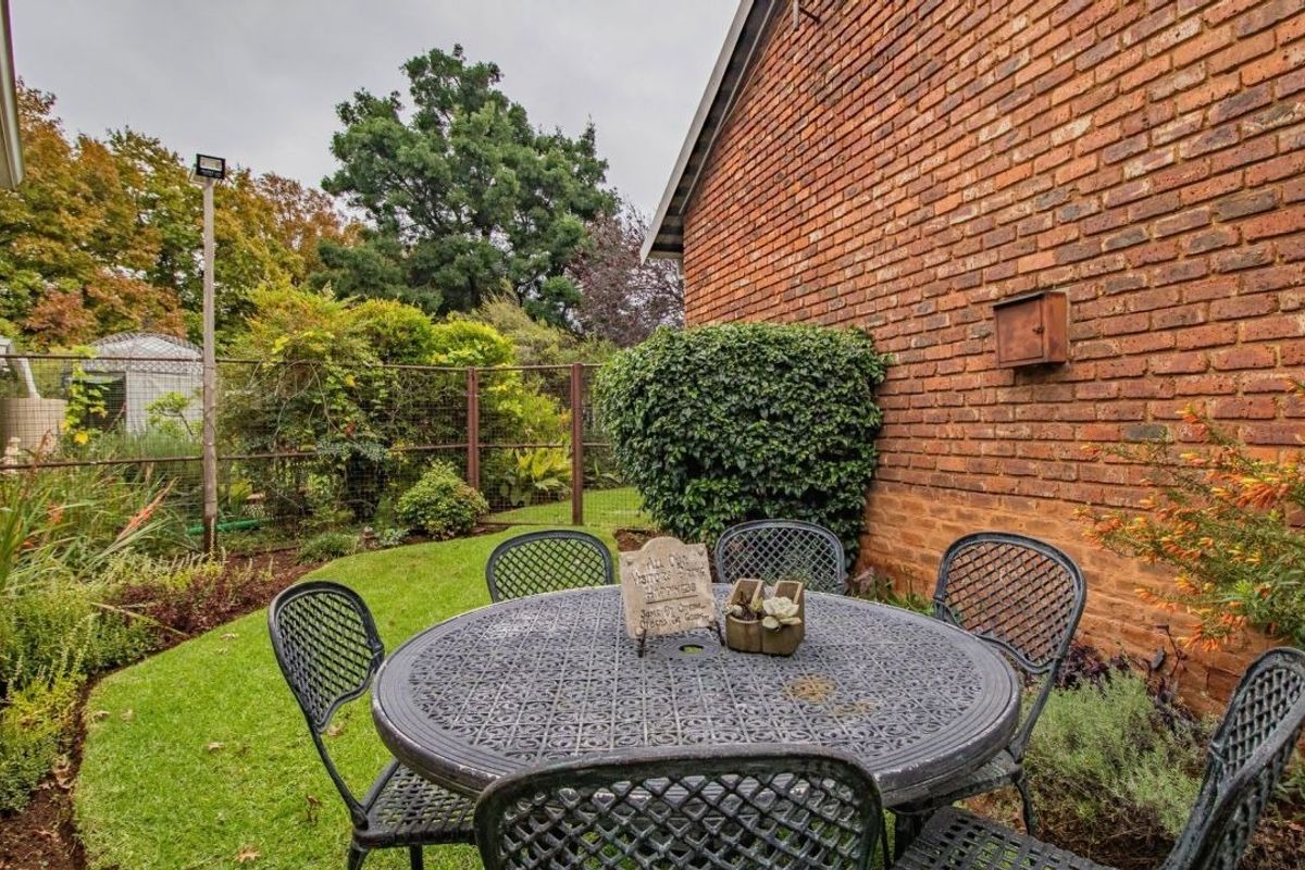 A private rear garden area featuring a brick wall facade, established lawn, and perimeter fencing, providing a quiet outdoor space.
