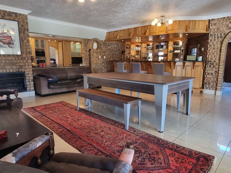Spacious open-plan living area featuring a built-in wooden bar, brick fireplace, and tiled flooring, offering a versatile layout for entertaining.