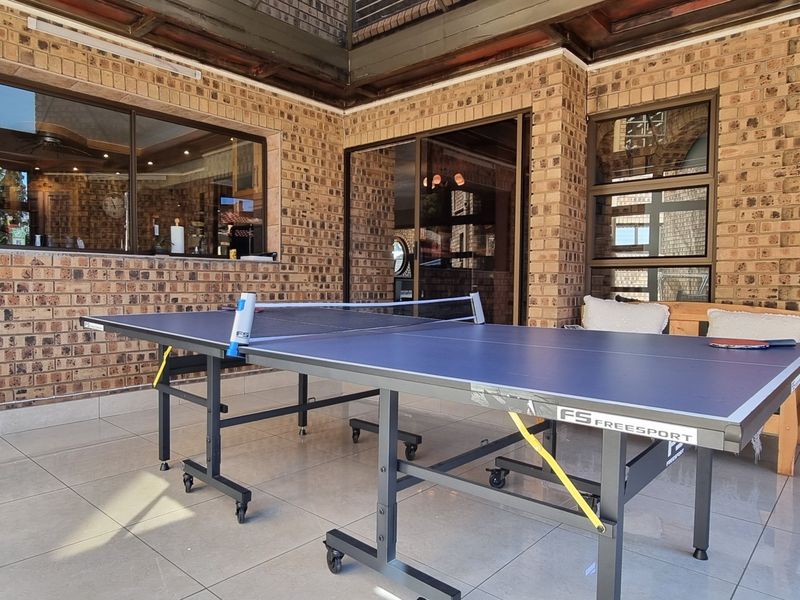 A covered patio area featuring exposed brick walls, tiled flooring, and sliding glass doors providing access to the interior living space.