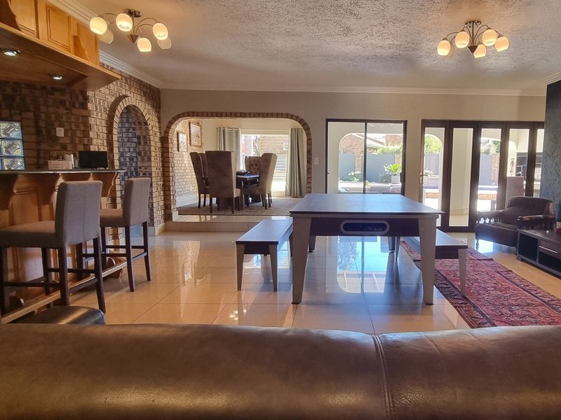Spacious open-plan living area featuring a built-in bar, distinctive brick archways, tiled flooring, and direct access to the outdoor patio through sliding glass doors.