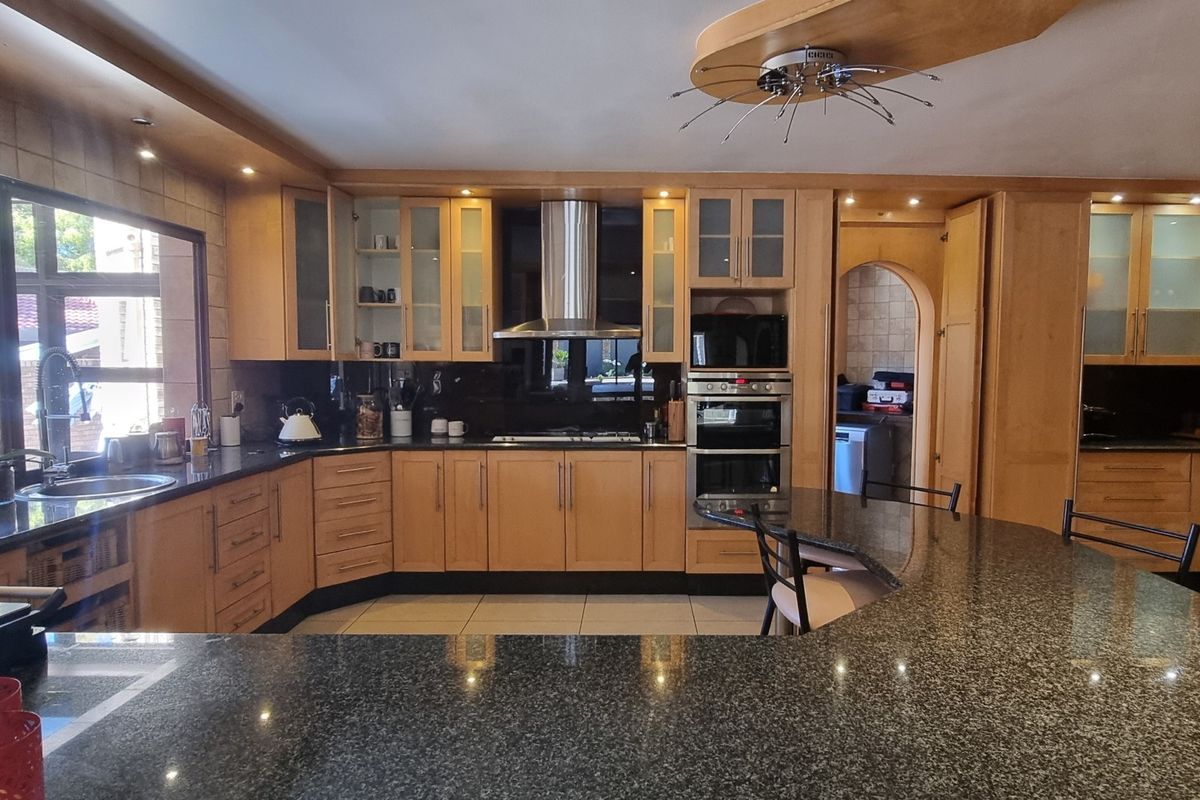 Spacious kitchen featuring extensive wooden cabinetry, granite countertops, built-in appliances, and a large breakfast bar island with recessed lighting.