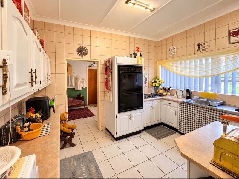 A functional kitchen featuring built-in oven, cooktop, tiled splashbacks, and ample cabinetry, offering a classic layout with potential for modern updates.