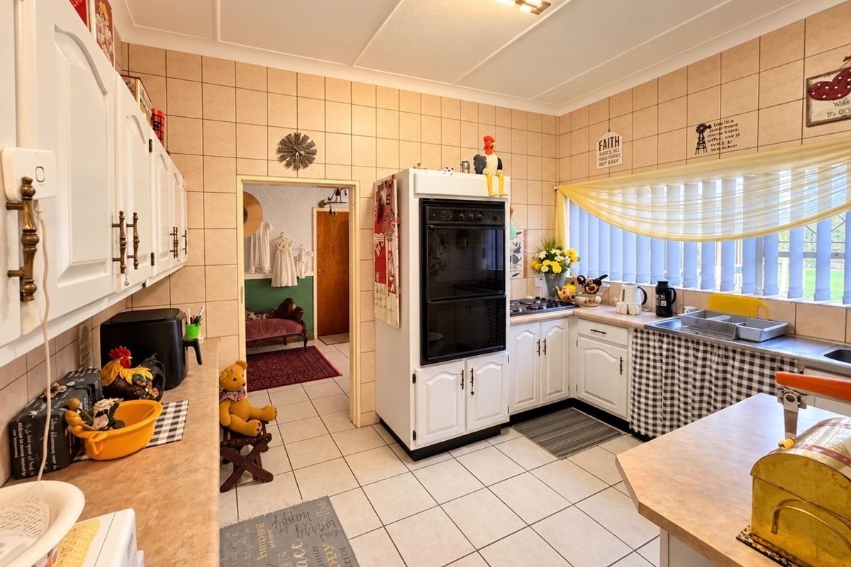 A functional kitchen featuring built-in oven, cooktop, tiled splashbacks, and ample cabinetry, offering a classic layout with potential for modern updates.