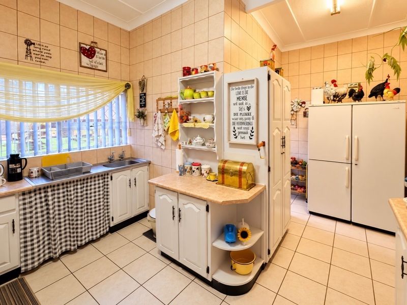 A functional kitchen featuring tiled walls and flooring, built-in white cabinetry, laminate countertops, and a stainless steel sink.