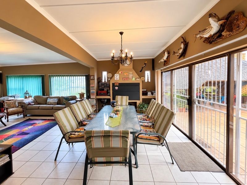 Spacious open-plan living and dining area featuring a built-in fireplace, tiled flooring, and large sliding doors providing access to the outdoor patio.