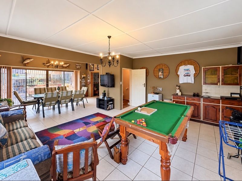 Spacious open-plan living and entertainment area featuring tiled flooring, built-in cabinetry, and direct access to the outdoor patio through sliding glass doors.